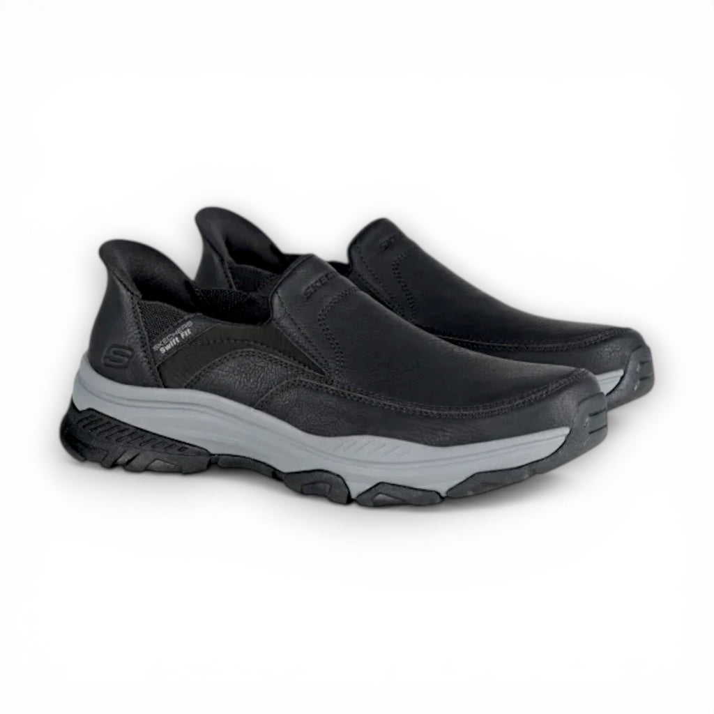 Black slip-on shoes with gray soles on a white background