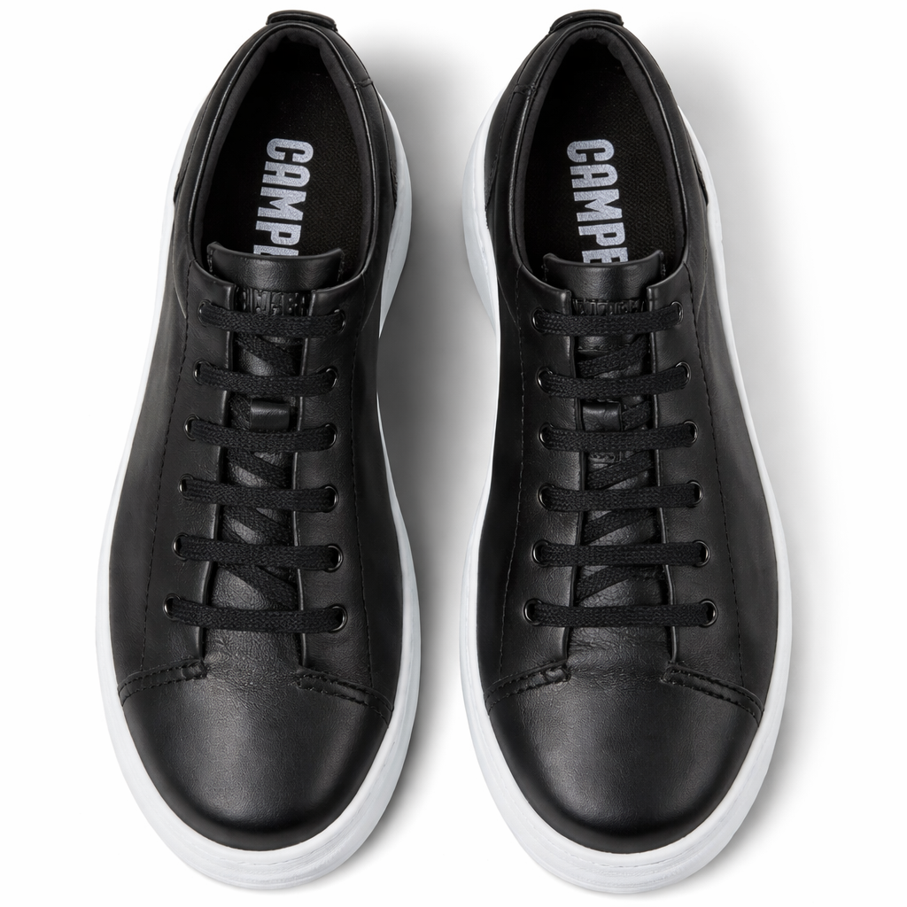 Black leather sneakers with white soles on a light gray background